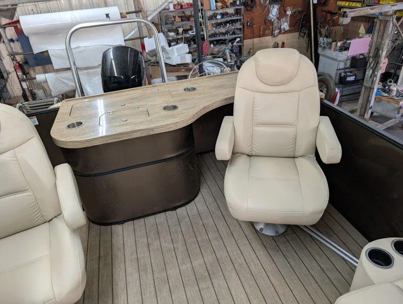 Slide: The Image of 2018 Sylvan Mirage Cruise 8524 Entertainer boat interior with beige seating and wooden deck. - 8