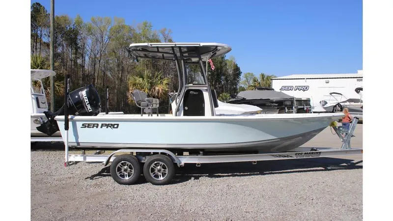 Slide: The Image of 2025 Sea Pro 230 Bay boat on trailer, parked outdoors under clear blue sky. - 8