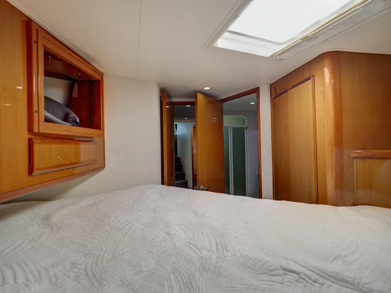 Slide: The Image of 2001 Viking Convertible yacht interior with cozy bedroom, wooden cabinets, and skylight. - 19