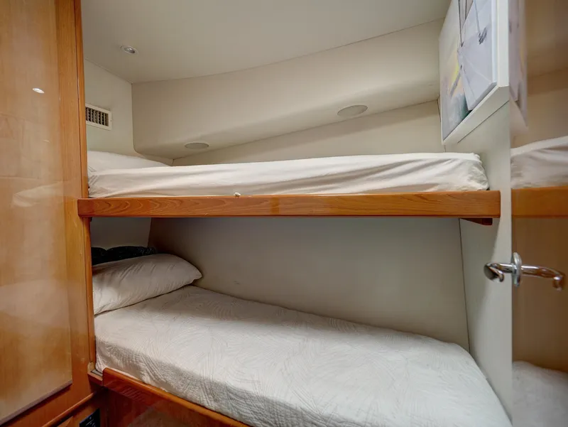 Slide: The Image of Bunk beds in 2001 Viking Convertible yacht cabin, featuring wooden frames and white bedding. - 22