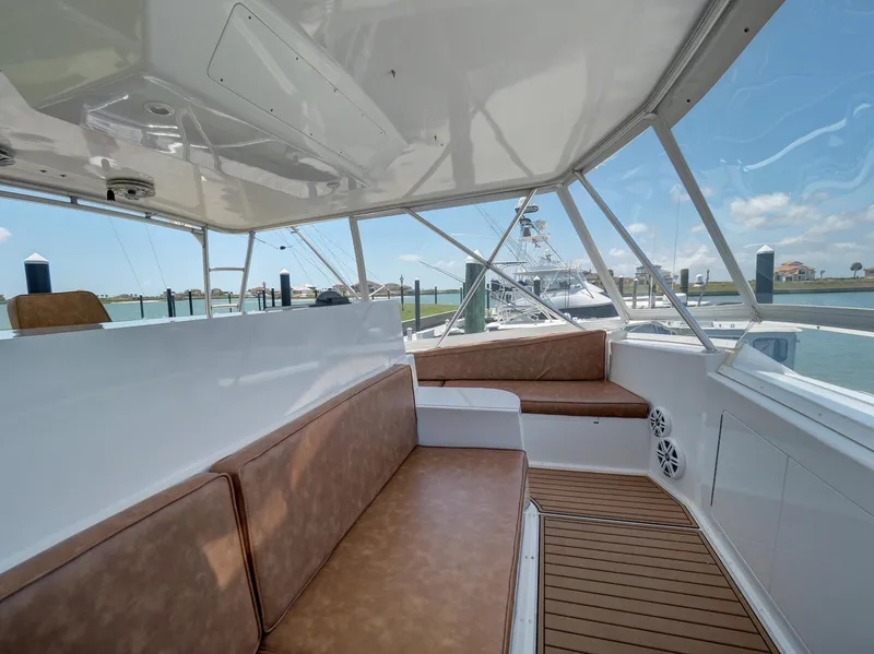 Slide: The Image of 2001 Viking Convertible boat interior with brown seating and wooden flooring at a marina. - 28