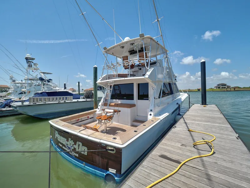 Slide: The Image of 2001 Viking Convertible yacht docked, featuring fishing equipment and clear blue skies. - 30