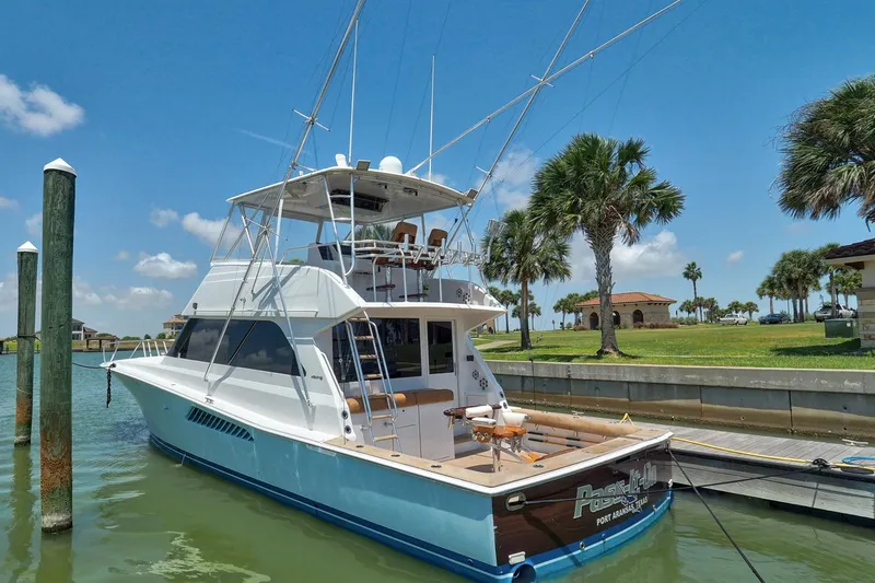 Slide: The Image of 2001 Viking Convertible yacht docked by palm trees under a clear blue sky. - 31