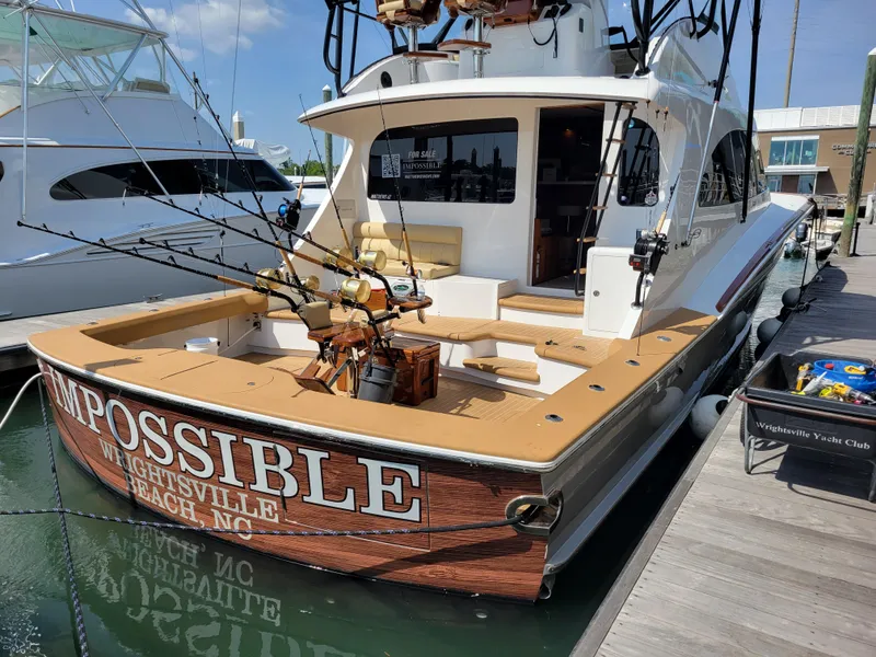 Slide: The Image of 2024 Matthews 62 Sport Fish boat docked, featuring fishing rods and a spacious deck. - 26