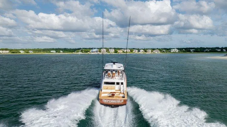 Slide: The Image of 2024 Matthews 62 Sport Fish cruising on open water, creating a wake under a partly cloudy sky. - 29