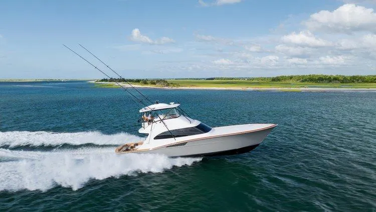 Slide: The Image of 2024 Matthews 62 Sport Fish yacht cruising on open water, clear sky, scenic coastline. - 3