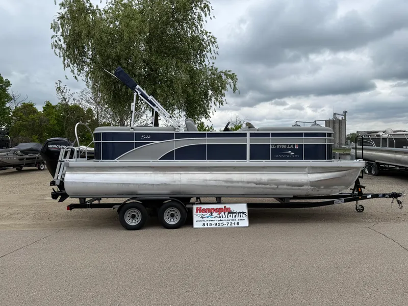 Slide: The Image of 2021 Bennington 22 SSR pontoon boat on trailer, parked outdoors under cloudy sky. - 0