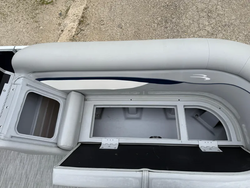 Slide: The Image of 2021 Bennington 22 SSR boat seat storage compartment, open and empty, with gray upholstery. - 25
