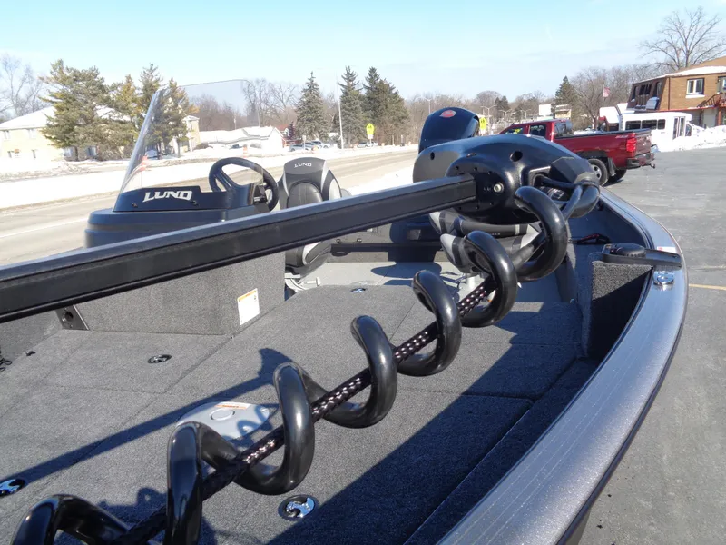 Slide: The Image of 2025 Lund 1875 Impact XS SS boat with trolling motor on deck, parked outdoors. - 14