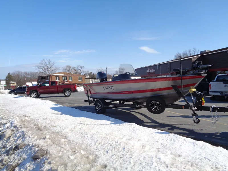 Slide: The Image of 2025 Lund 1875 Impact XS SS boat on trailer in snowy parking lot. - 31