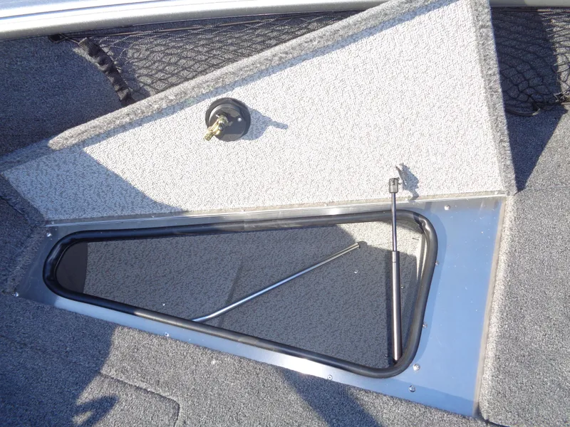 Slide: The Image of 2025 Lund 1875 Impact XS SS boat storage compartment with open hatch and carpeted interior. - 34