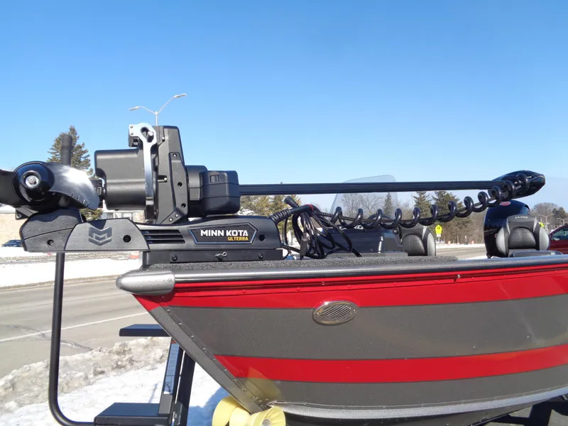 Slide: The Image of 2025 Lund 1875 Impact XS SS boat with Minn Kota motor, parked on snowy roadside. - 4