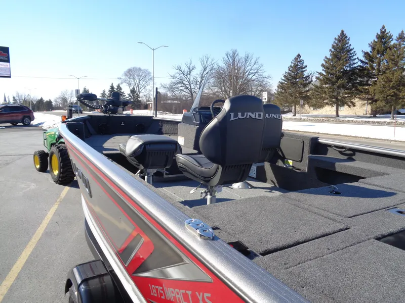 Slide: The Image of 2025 Lund 1875 Impact XS SS boat with seating, parked outdoors on a sunny day. - 5