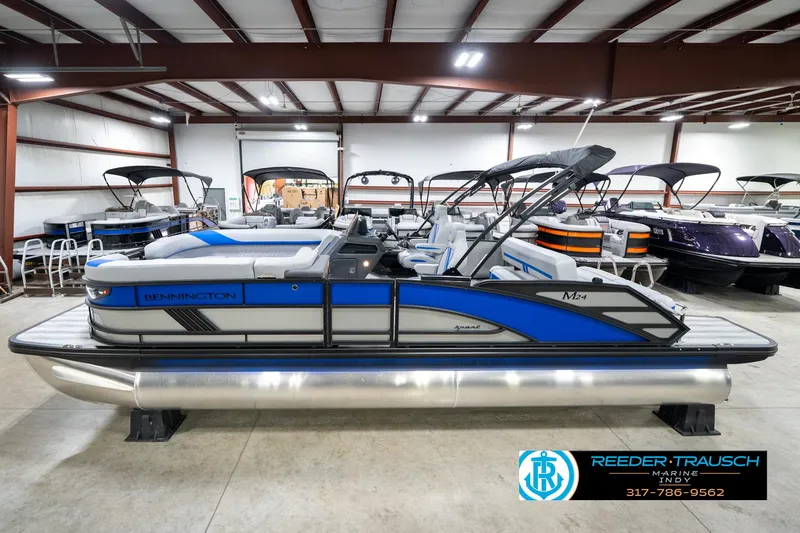 Slide: The Image of 2025 Bennington 24 MSB pontoon boat in showroom, featuring sleek blue and gray design. - 1