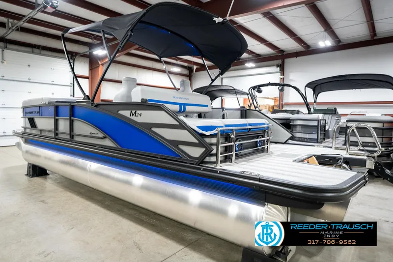 Slide: The Image of 2025 Bennington 24 MSB pontoon boat with blue accents in a showroom. - 10