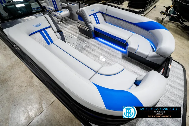 Slide: The Image of 2025 Bennington 24 MSB pontoon boat interior with blue and gray seating, showcased by Reeder-Trausch Marine. - 13