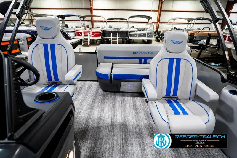 Slide: The Image of 2025 Bennington 24 MSB pontoon boat interior with blue-striped seating in showroom. - 17