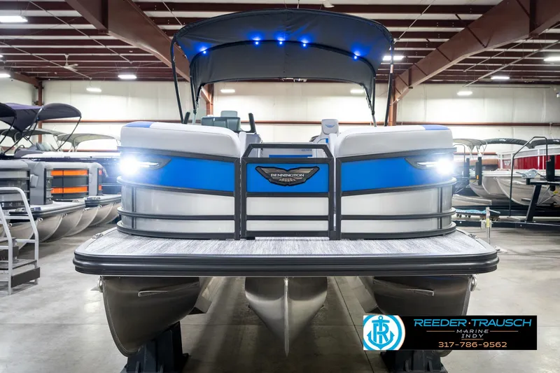 Slide: The Image of 2025 Bennington 24 MSB pontoon boat in showroom with blue accents and LED lights. - 5