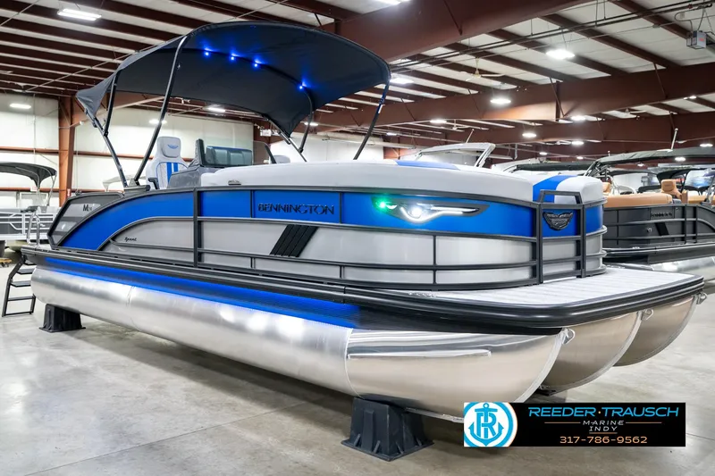 Slide: The Image of 2025 Bennington 24 MSB pontoon boat with blue accents in a showroom. - 6