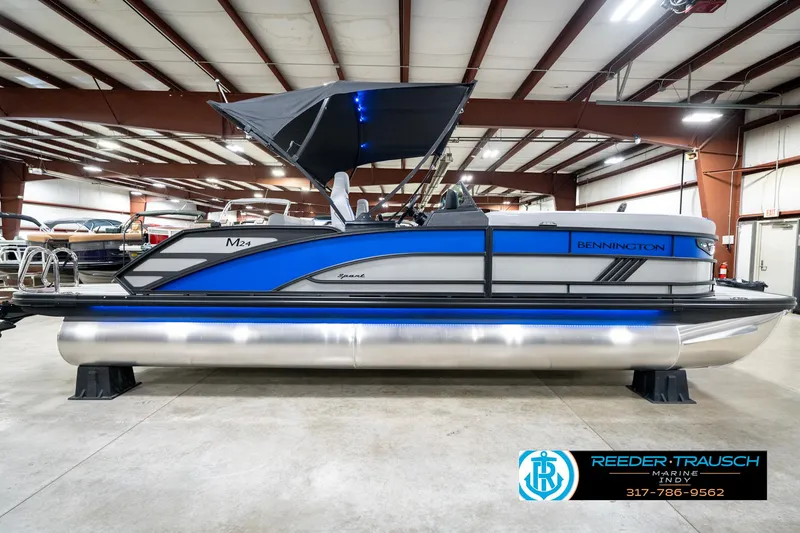 Slide: The Image of 2025 Bennington 24 MSB pontoon boat in showroom, featuring sleek blue and silver design. - 7