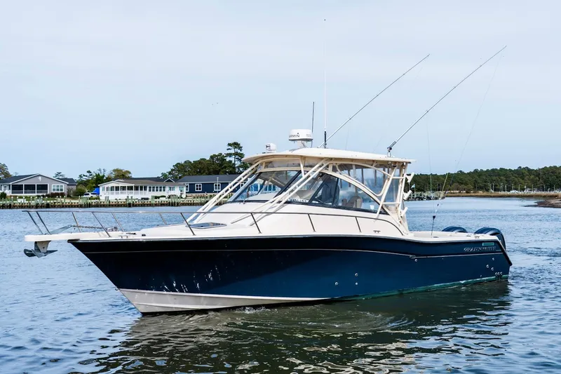 Slide: The Image of 2015 Grady-White 330 Express boat on calm water, with coastal homes in the background. - 2