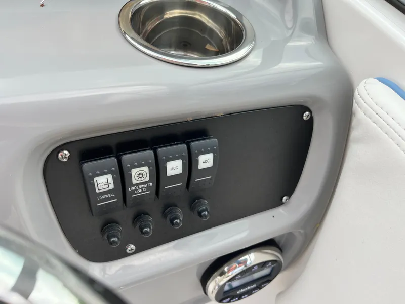 Slide: The Image of Control panel of 2024 Robalo R207 Dual Console boat with switches and cup holder. - 13