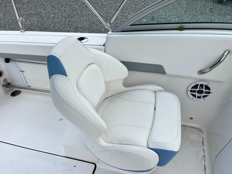 Slide: The Image of 2024 Robalo R207 Dual Console boat seat, white with blue accents, near speaker and handle. - 20