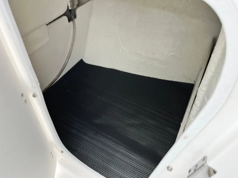 Slide: The Image of 2024 Robalo R207 Dual Console interior storage compartment with black mat flooring. - 22