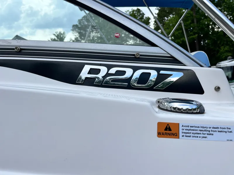 Slide: The Image of 2024 Robalo R207 Dual Console boat with warning label and sleek design. - 6