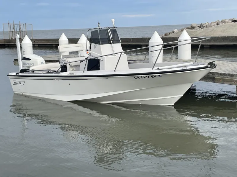 Slide: The Image of 1996 Boston Whaler 21 Outrage boat docked on calm water. - 2