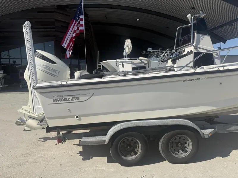 Slide: The Image of 1996 Boston Whaler 21 Outrage boat on trailer with Suzuki engine and American flag. - 7