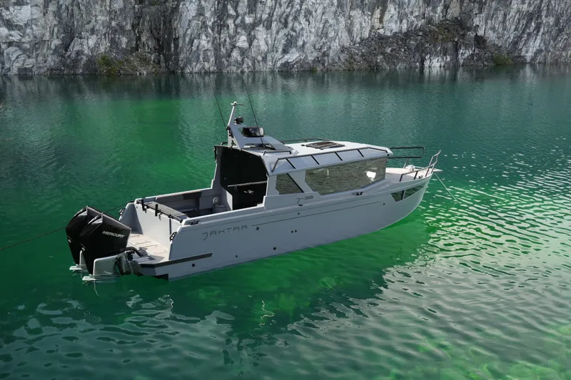Slide: The Image of Jaktar J30 Black Vision 2026 boat on serene green water near rocky cliffs. - 11