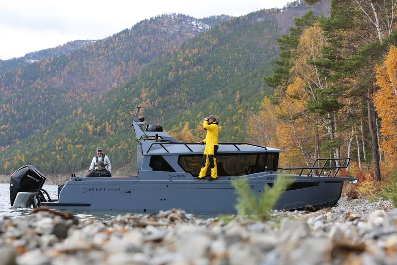 Slide: The Image of 2026 Jaktar J30 Black Vision boat in scenic autumn landscape with people on board. - 2