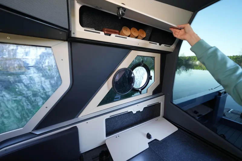 Slide: The Image of Interior of 2026 Jaktar J30 Black Vision boat with storage compartment and porthole view. - 48