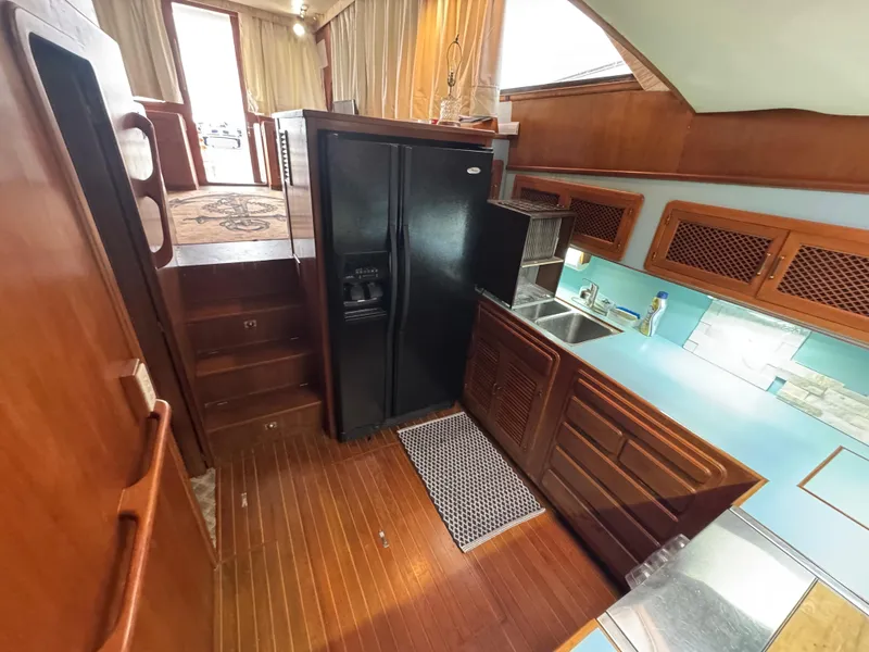 Slide: The Image of 1989 Ricker 48 Convertible yacht kitchen with wood cabinetry and black refrigerator. - 12
