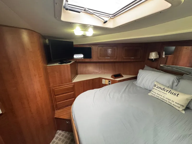 Slide: The Image of 1989 Ricker 48 Convertible yacht cabin with bed, TV, and wooden cabinetry. - 15