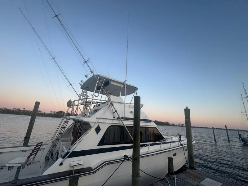 Slide: The Image of 1989 Ricker 48 Convertible yacht docked at sunset, calm waters, clear sky. - 18