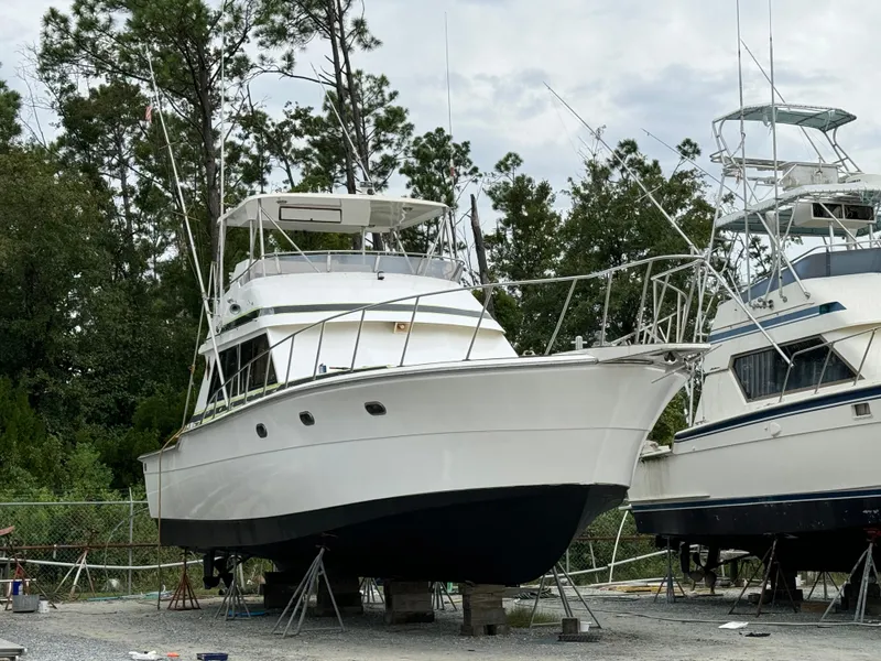 Slide: The Image of 1989 Ricker 48 Convertible yacht on dry dock, surrounded by trees and other boats. - 22