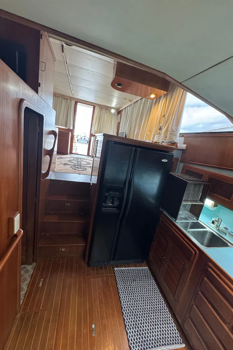 Slide: The Image of 1989 Ricker 48 Convertible yacht interior with kitchen, wooden flooring, and stairs. - 38