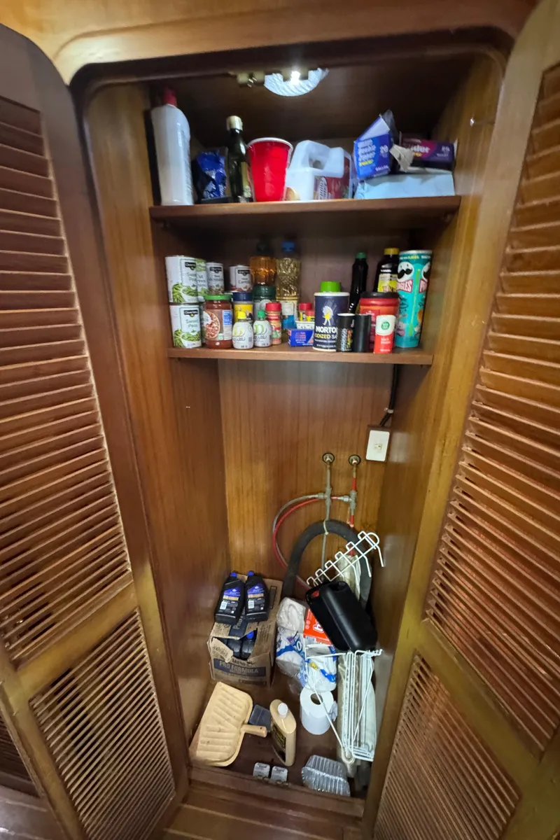 Slide: The Image of Pantry inside 1989 Ricker 48 Convertible yacht, stocked with various food and household items. - 32