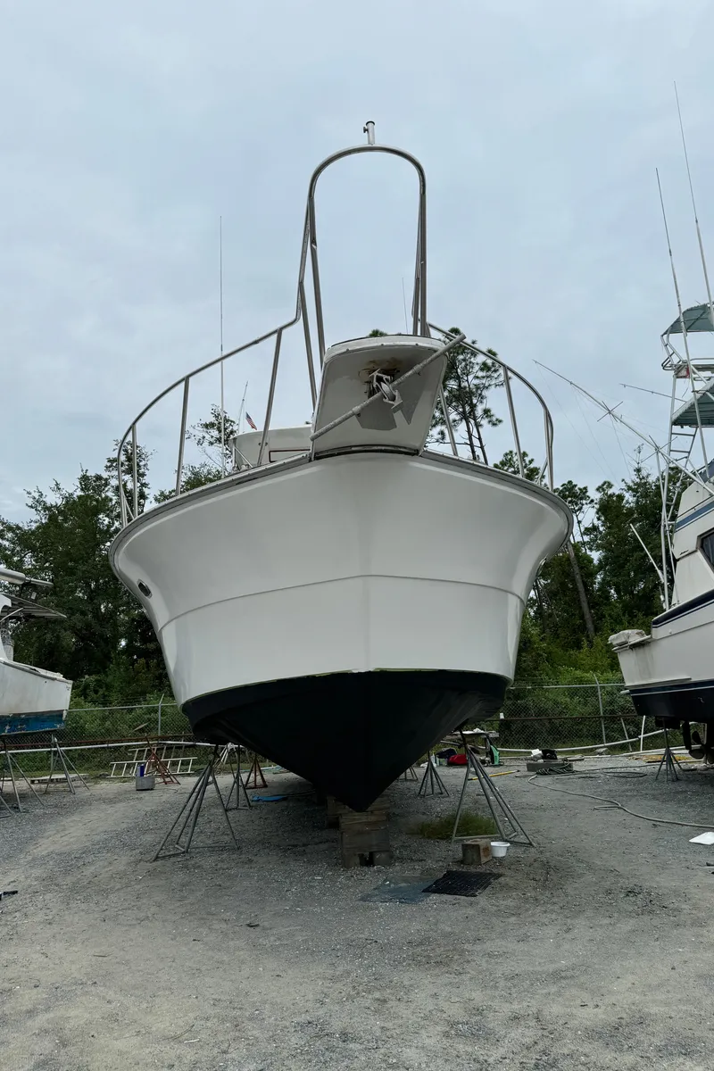 Slide: The Image of 1989 Ricker 48 Convertible boat on dry dock, front view, with overcast sky. - 40