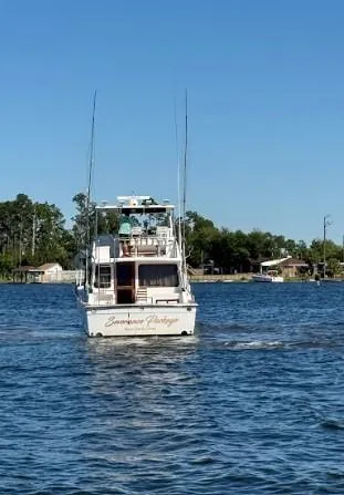 Slide: The Image of 1989 Ricker 48 Convertible yacht cruising on a serene lake under a clear blue sky. - 25