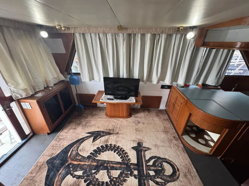Slide: The Image of Interior of 1989 Ricker 48 Convertible yacht with anchor-themed rug and TV setup. - 6