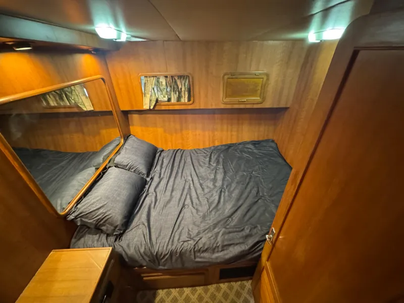 Slide: The Image of 1989 Ricker 48 Convertible yacht cabin with wood paneling and cozy bedding. - 9