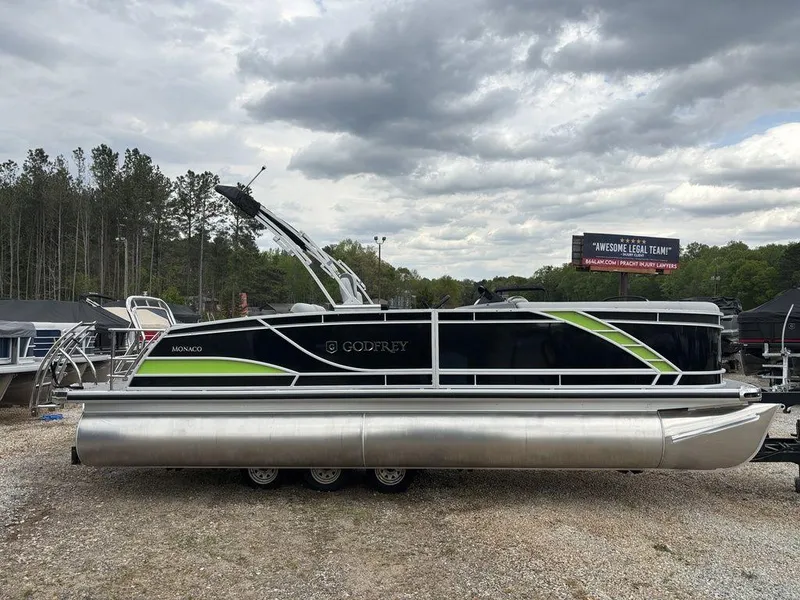 Slide: The Image of 2025 Godfrey Monaco 235 DFL pontoon boat with sleek design, parked outdoors. - 6