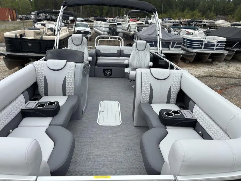 Slide: The Image of 2025 Godfrey Monaco 235 DFL pontoon boat with luxurious seating and cup holders, docked at marina. - 7