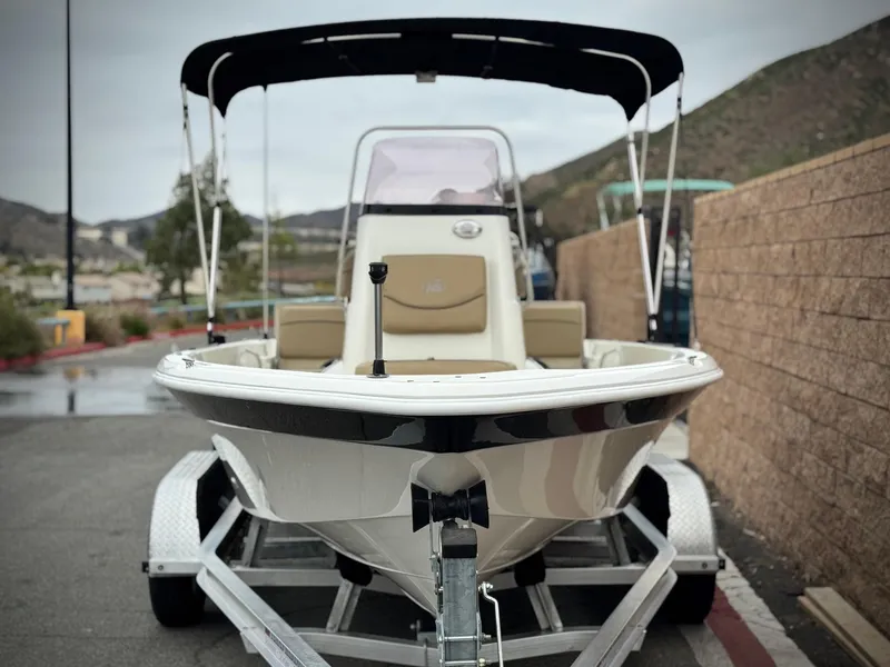 Slide: The Image of 2018 NauticStar 1910 boat on trailer with canopy, parked outdoors. - 2