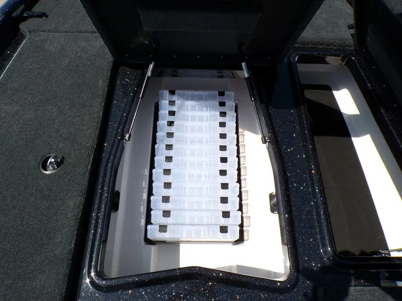 Slide: The Image of 2025 Skeeter ZXR19 storage compartment with organized tackle boxes. - 13