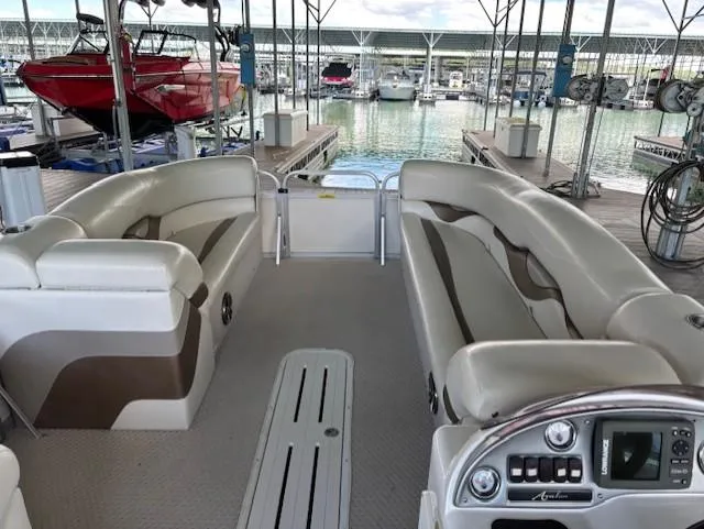 Slide: The Image of 2007 Avalon Windjammer RC 22' pontoon boat interior with beige seating at marina. - 10