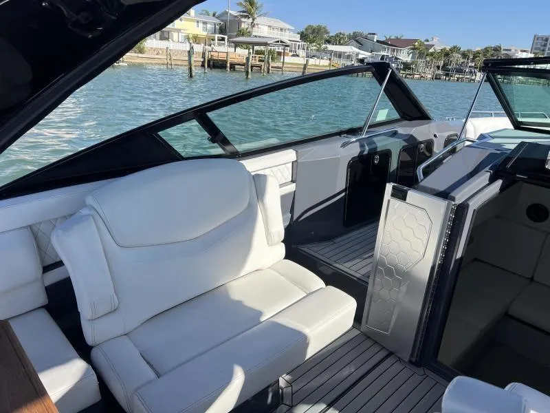 Slide: The Image of 2020 Cruisers Yachts 338OB interior with white seating, dockside view, and open water backdrop. - 10